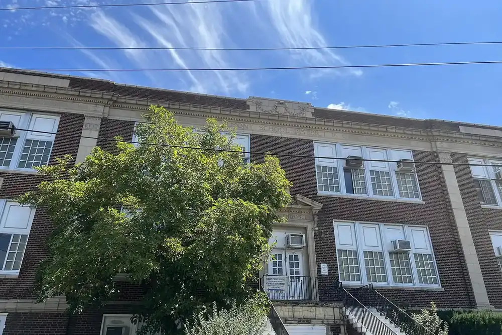 Elmont Road School, a tall brick school building under a bright blue sky in Elmont, New York
