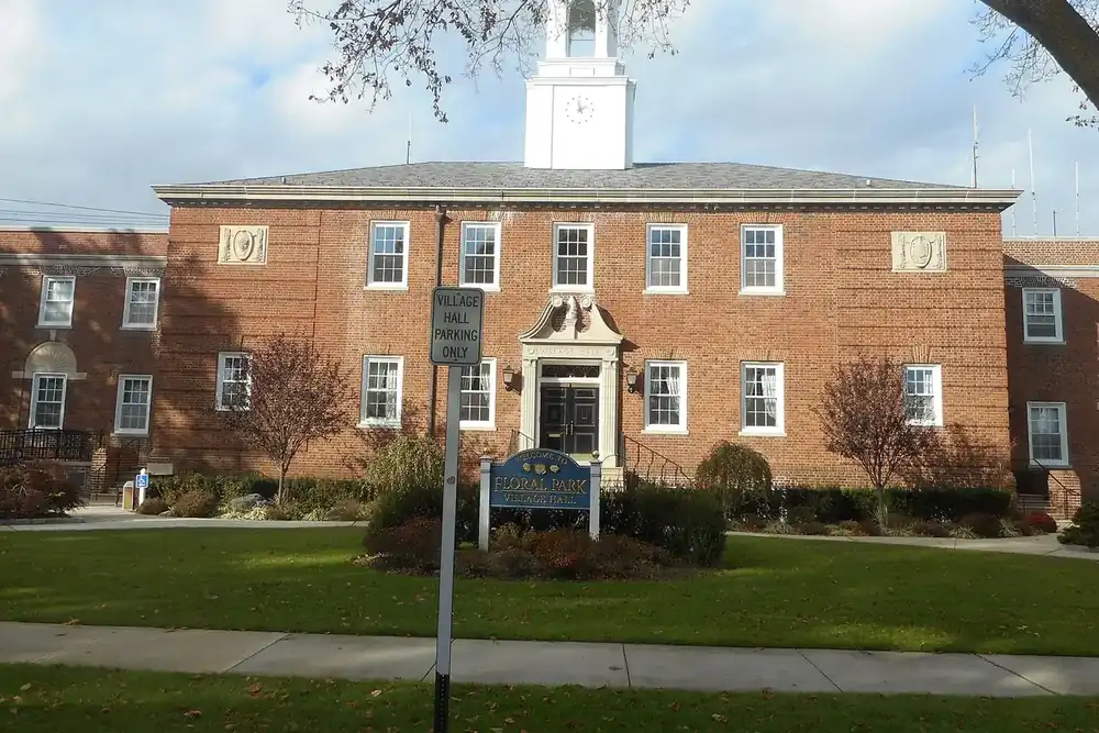 Floral Park Village Hall, a red brick building with a white cupola and lawn